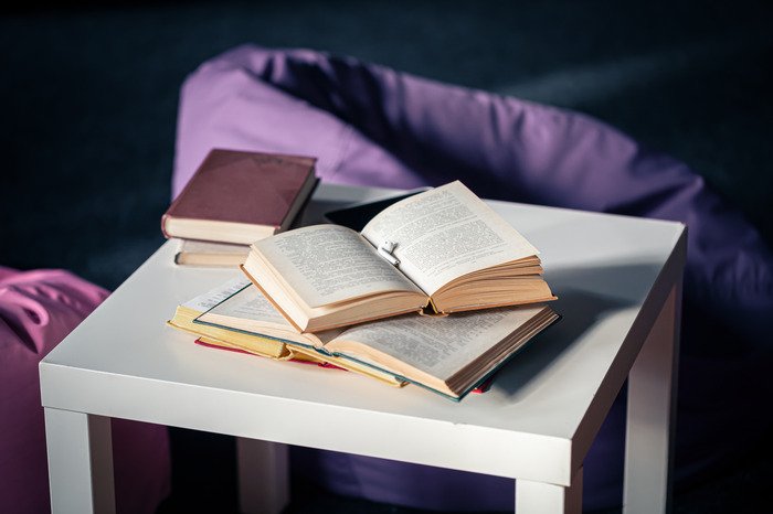 Creative Writing books small white table blurred background interior with poufs 1